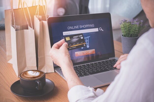 Empresaria que usa el ordenador portátil que paga el carro del crédito, concepto de compras en línea.