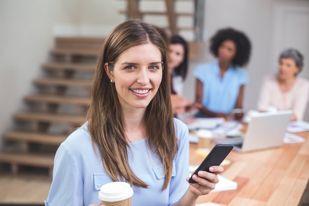 Empresaria que usa el teléfono móvil mientras que tomando café