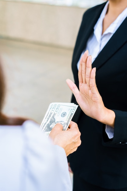 Foto empresaria rechazando el dinero ofrecido por una mujer