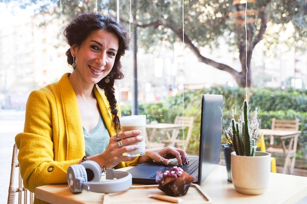 Empresária segura uma cafeteria sorridente em uma cafeteria