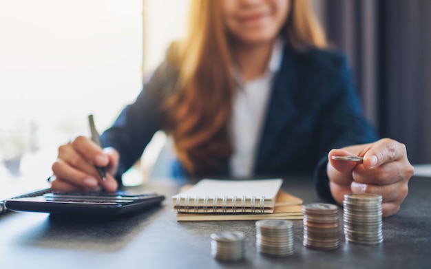 Empresária segurando e empilhando moedas enquanto calcula o dinheiro na mesa