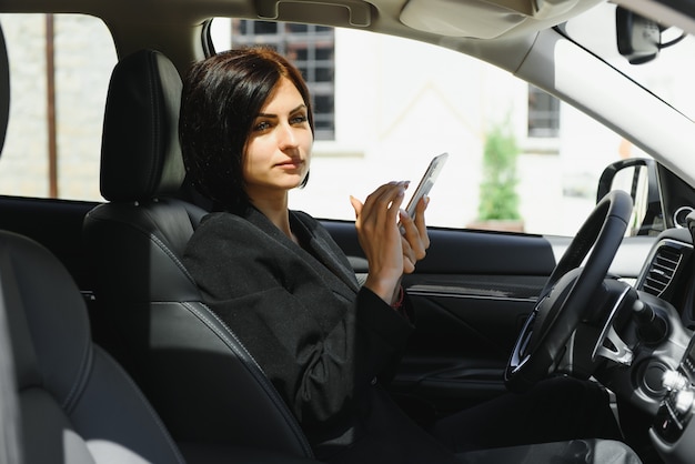 Empresaria sentada en el asiento del conductor en su automóvil usando el teléfono