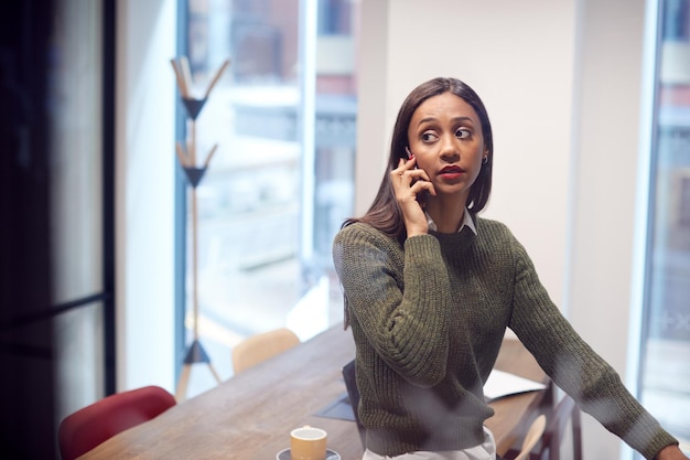 La empresaria sentada en el escritorio en la sala de reuniones hablando por teléfono móvil