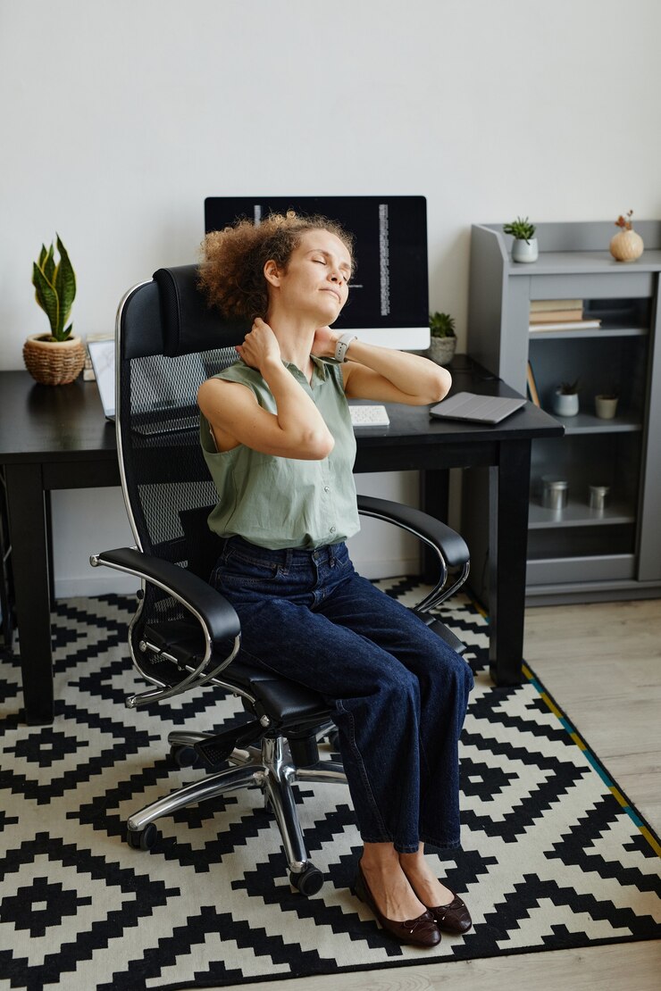 Foto empresária sentada na cadeira se espreguiçando, parecendo exausta e cansada do trabalho