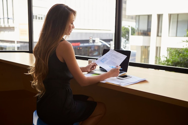 Empresária sentada no escritório moderno lendo um documento