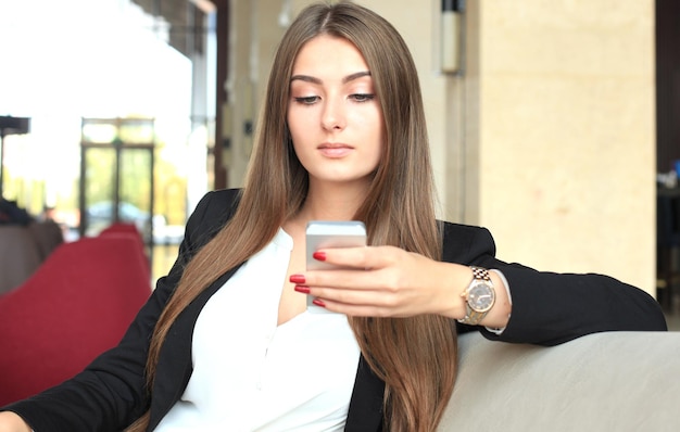 Empresária sentada sofá usando smartphone na cafeteria.