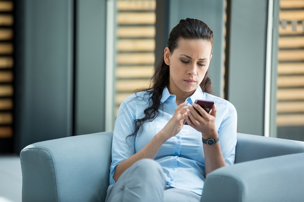 Empresária sentado e usando um telefone celular