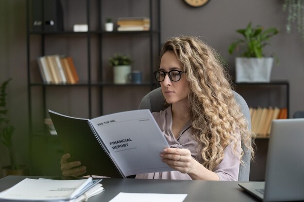 Empresaria seria joven que mira a través de documentos financieros