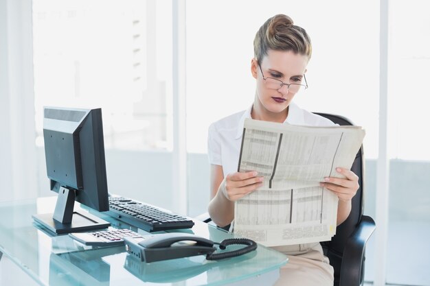 Foto empresaria seria leyendo el periódico