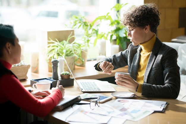 Empresaria seria que controla el tiempo en la reunión en café