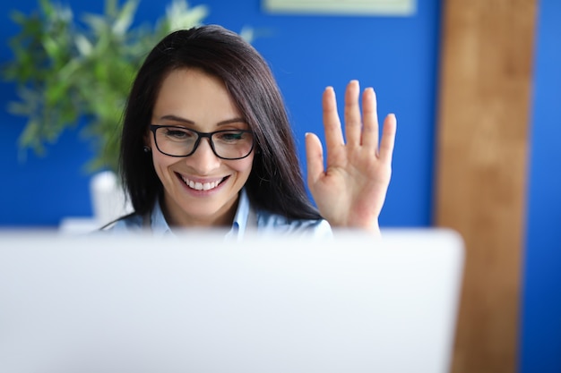 Foto la empresaria se sienta en la computadora y prevalece sobre el interlocutor con su mano