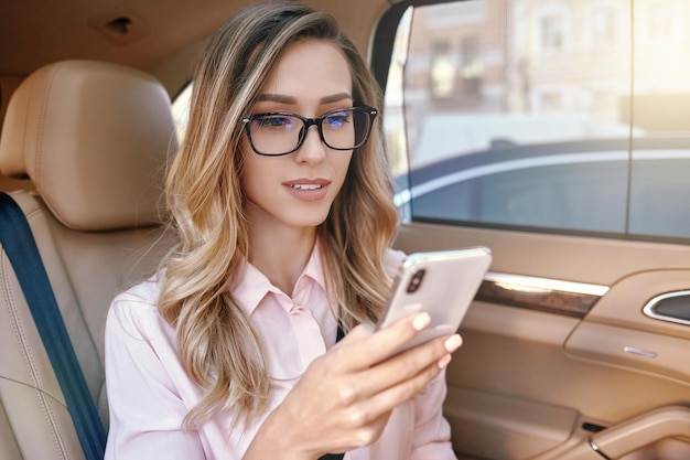 Empresaria con smartphone en el coche