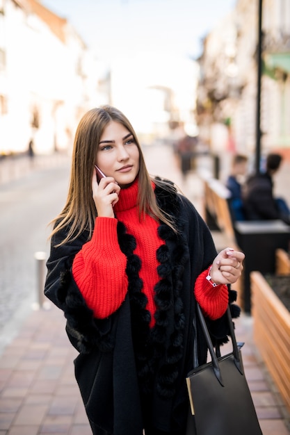 Empresaria sofisticada en vestido hablando por teléfono en la calle