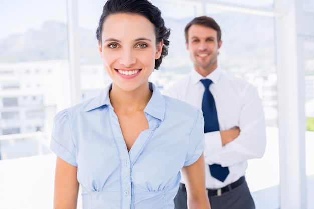 Empresaria sonriente con colega masculino en el fondo