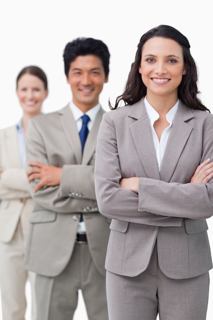 Empresaria sonriente con equipo y brazos cruzados