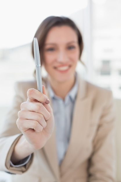 Empresaria sonriente extendiendo un lápiz en la oficina