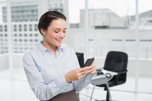 Empresaria sonriente leyendo mensajes de texto en la oficina