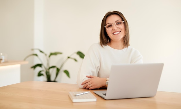 Empresaria sonriente con portátil trabajando en la mesa