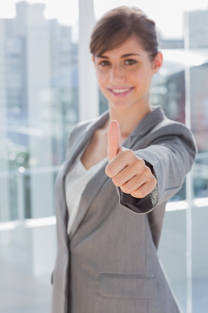 Empresaria sonriente que da el pulgar para arriba