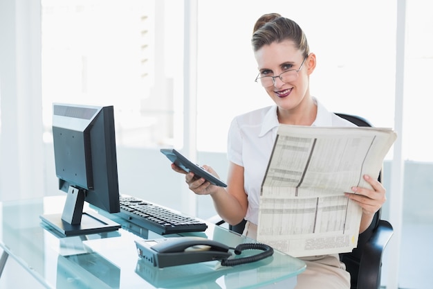 Empresaria sonriente que sostiene el periódico y la calculadora