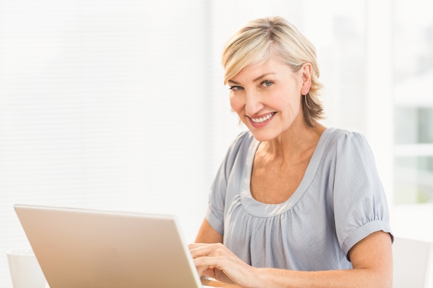 Empresaria sonriente que trabaja en una computadora portátil