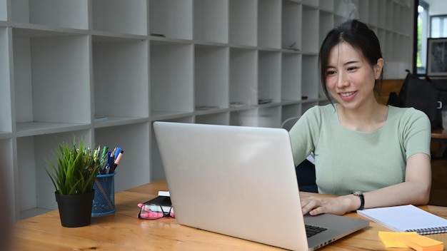 Empresaria sonriente que trabaja con una computadora portátil