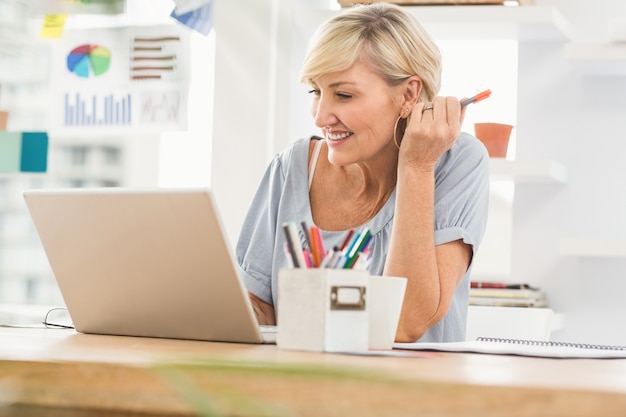 Empresaria sonriente que trabaja en su computadora portátil