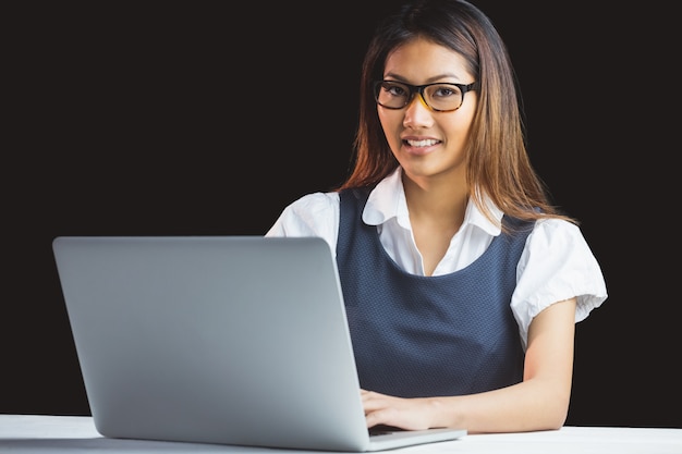 Empresaria sonriente que usa la computadora portátil en fondo negro