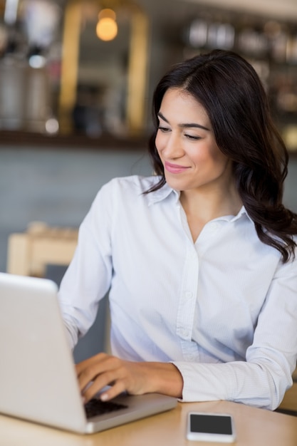 Empresaria sonriente que usa la computadora portátil