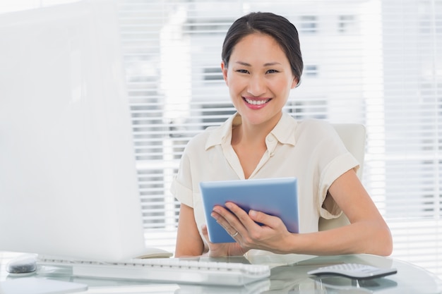 Empresaria sonriente que usa la tableta digital en el escritorio