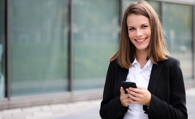 Empresaria sonriente que usa un teléfono inteligente al aire libre