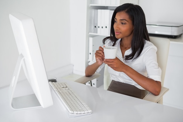 Empresaria sonriente tomando un café en su escritorio