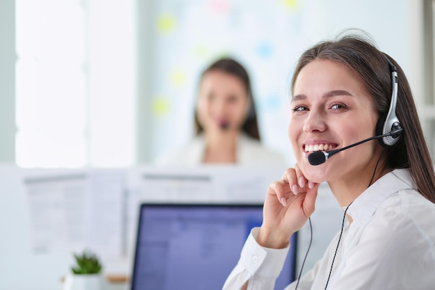 Empresaria sonriente u operador de línea de ayuda con auriculares y computadora en la oficina