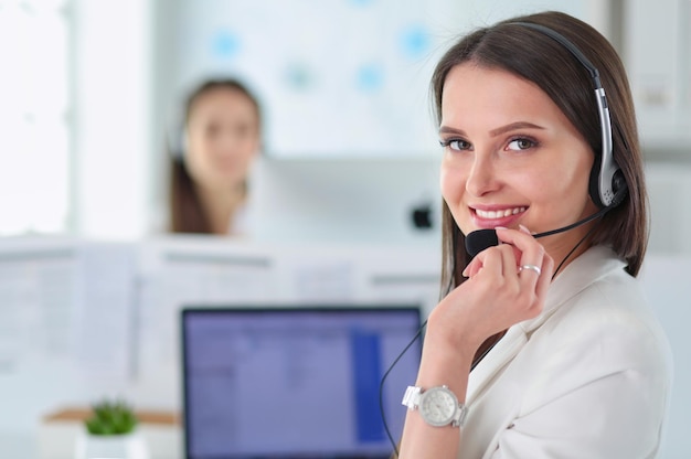 Foto empresaria sonriente u operador de línea de ayuda con auriculares y computadora en la oficina