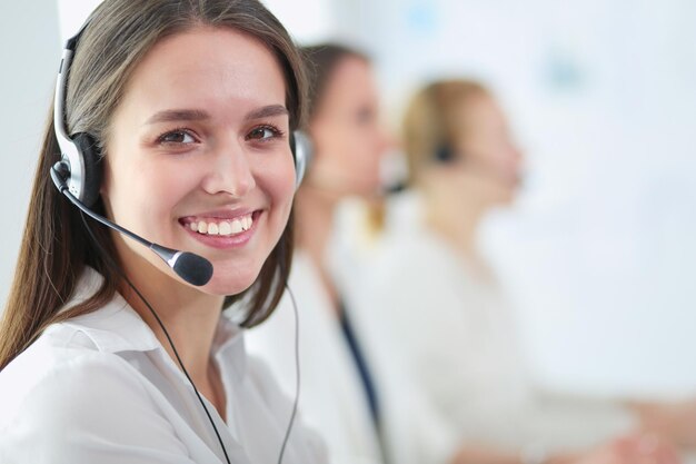 Empresaria sonriente u operador de línea de ayuda con auriculares y computadora en la oficina