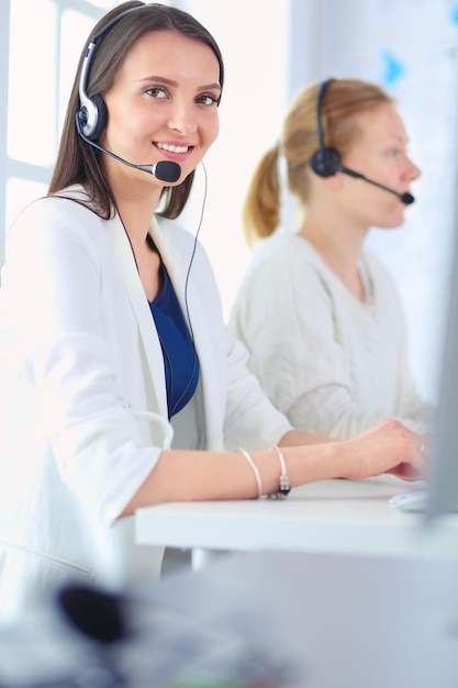 Empresaria sonriente u operador de línea de ayuda con auriculares y computadora en la oficina