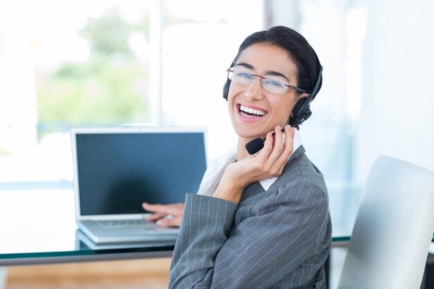 Empresaria sonriente usando un auricular de trabajo