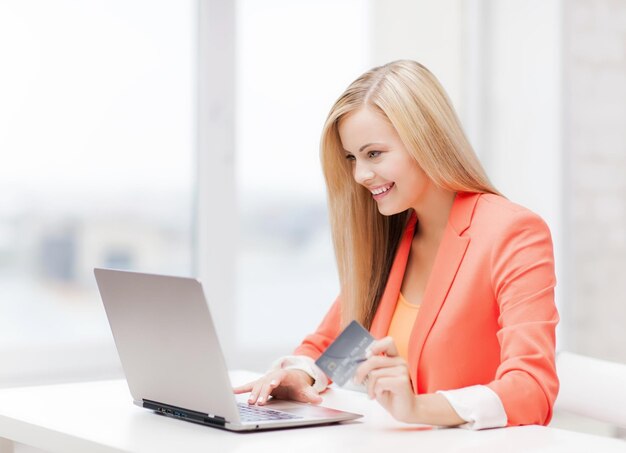 Empresária sorridente com laptop e cartão de crédito