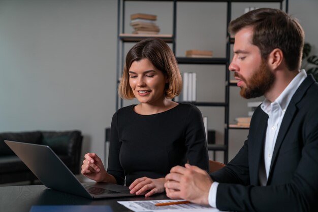 Empresária sorridente e empresário pensativo com roupa formal trabalhando juntos