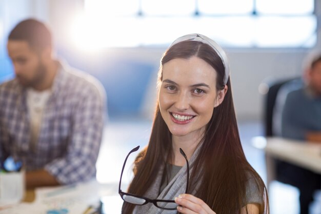 Empresária sorridente segurando óculos no escritório