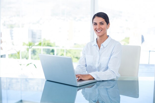 Empresária sorridente trabalhando com seu laptop