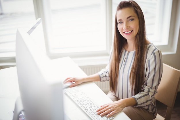 Empresária sorridente trabalhando no computador no escritório