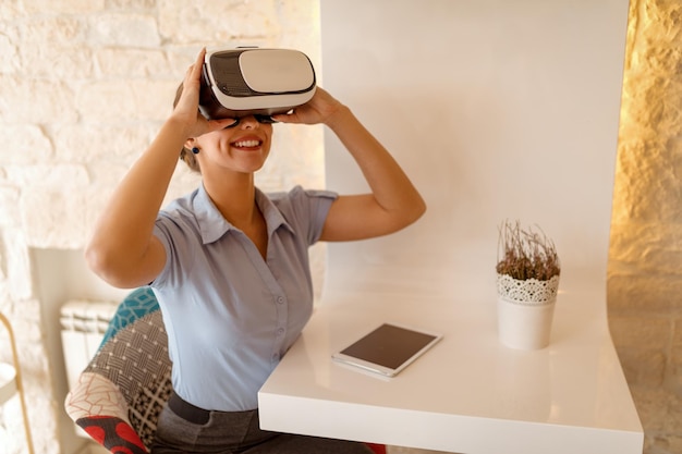 Empresária sorridente usando óculos de realidade virtual em um café.