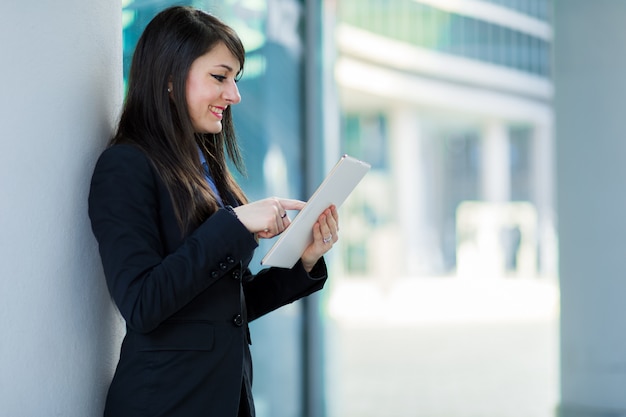 Empresária sorridente usando um tablet digital ao ar livre