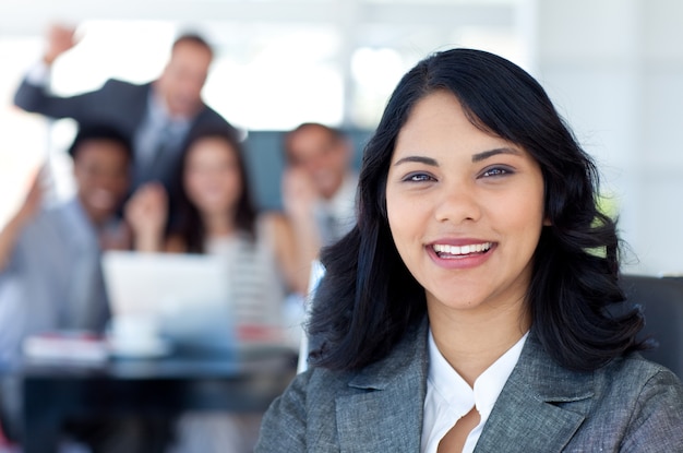 Empresária sorrindo com a equipe comemorando um sucesso no fundo