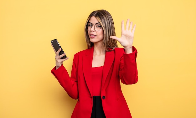 empresária sorrindo e parecendo amigável, mostrando o número cinco. conceito de smartphone