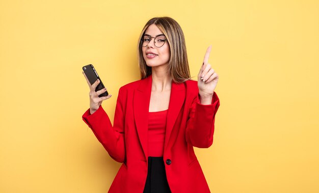 Empresária sorrindo e parecendo amigável, mostrando o número um. conceito de smartphone