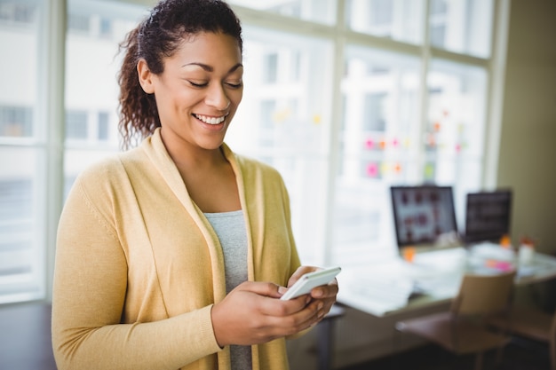 Empresária sorrindo enquanto estiver usando o telefone no escritório criativo