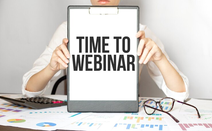 La empresaria sosteniendo una tarjeta con el texto TIME TO WEBINAR