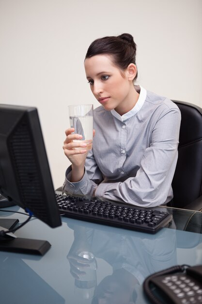 Empresaria en su escritorio con un vaso de agua